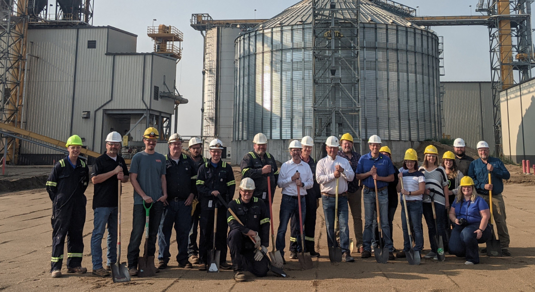 A group of people wearing hard hats and holding shovels.