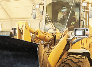 S&R Operators A man driving a yellow tractor in a garage.